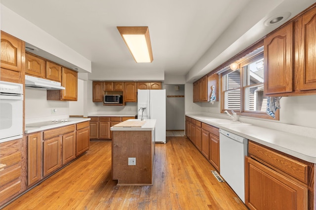 2398 S Williamsburg Dr, Plainfield, IL 60586 - kitchen with white appliances, under cabinet range hood, an island with sink, light wood finished floors, and light countertops