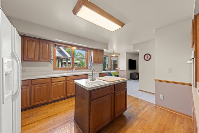 2398 S Williamsburg Dr, Plainfield, IL 60586 - kitchen with white refrigerator with ice dispenser, a kitchen island with sink, brown cabinetry, light wood finished floors, and light countertops