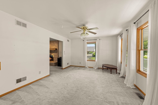 2398 S Williamsburg Dr, Plainfield, IL 60586 - spare room with light colored carpet, ceiling fan, and a brick fireplace