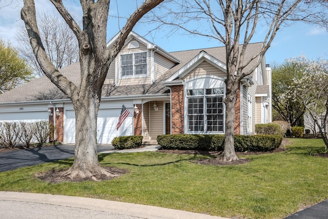 traditional-style house featuring a front yard, driveway, roof with shingles, and brick siding
