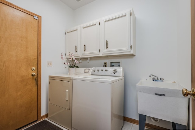 washroom featuring separate washer and dryer, cabinet space, baseboards, and a sink