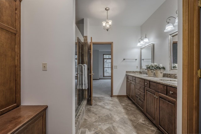 bathroom featuring a notable chandelier, walk in shower, double vanity, and a sink