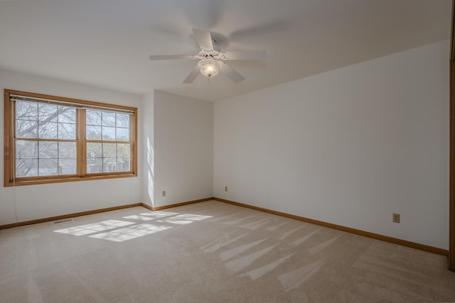 unfurnished room featuring baseboards, visible vents, ceiling fan, and light colored carpet