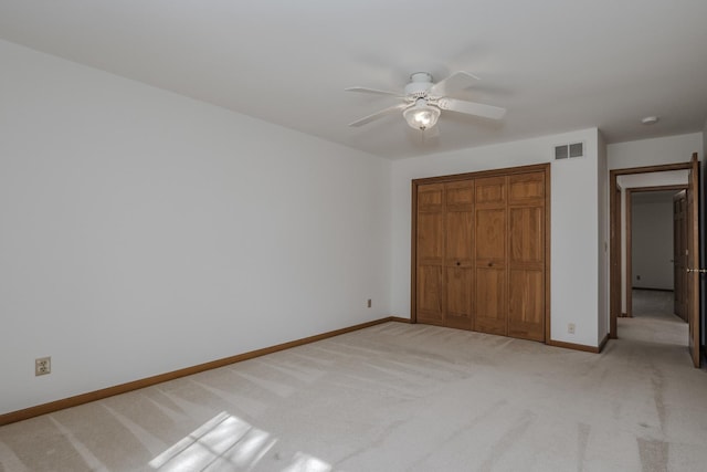 unfurnished bedroom featuring light colored carpet, a closet, ceiling fan, baseboards, and visible vents