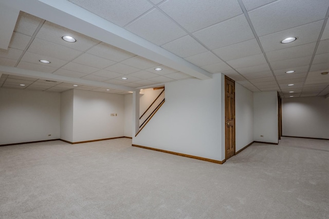 finished below grade area featuring light colored carpet, a paneled ceiling, recessed lighting, and baseboards