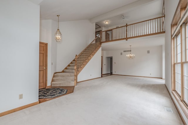 unfurnished living room featuring ceiling fan with notable chandelier, stairs, and carpet