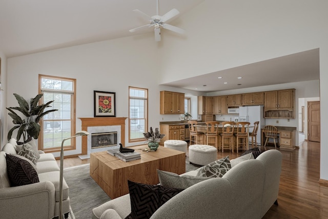living area featuring recessed lighting, a premium fireplace, high vaulted ceiling, ceiling fan, and wood finished floors