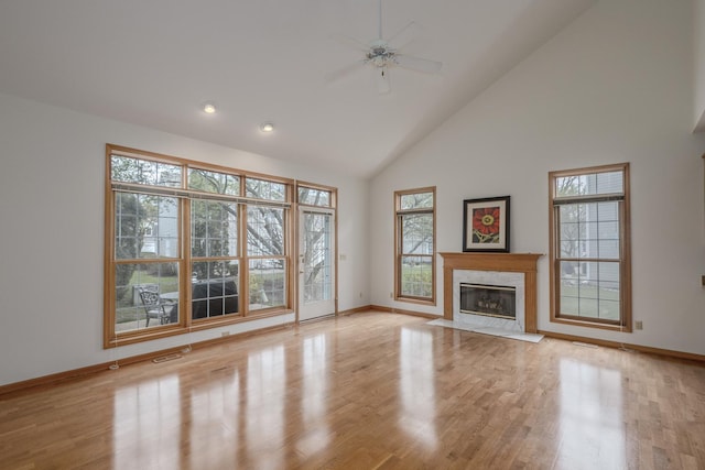 unfurnished living room with a fireplace, high vaulted ceiling, and baseboards