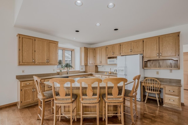 kitchen featuring recessed lighting, a sink, dark wood-style flooring, a kitchen island, and white appliances