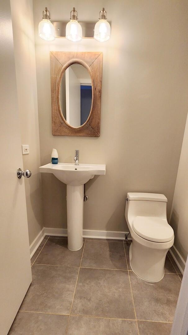 half bathroom featuring baseboards, toilet, and tile patterned flooring
