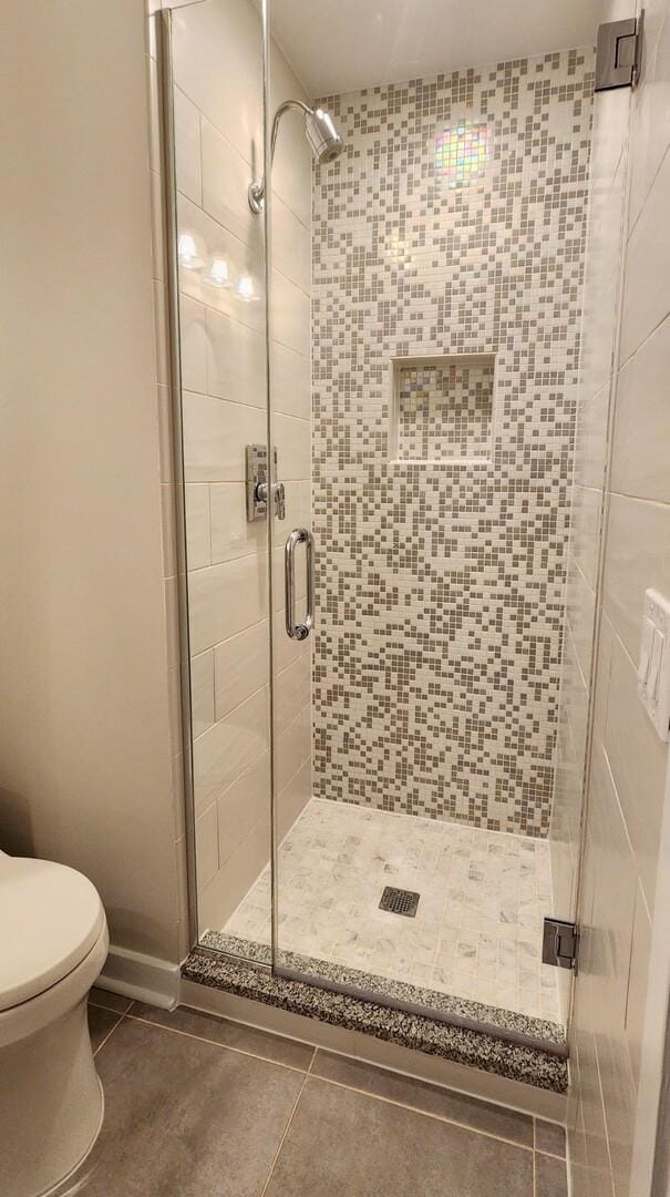 full bath featuring a shower stall, toilet, and tile patterned floors