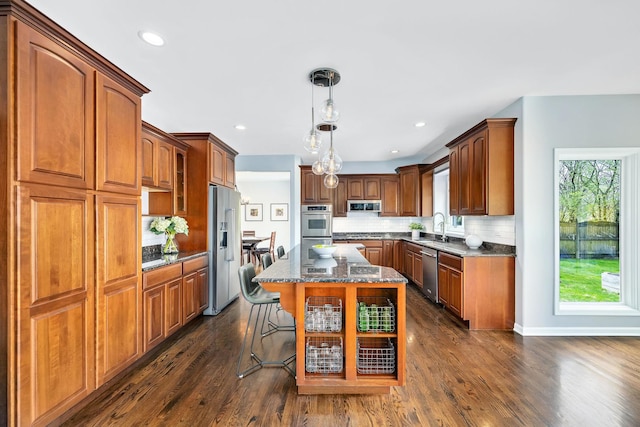 kitchen with tasteful backsplash, dark stone countertops, a breakfast bar, appliances with stainless steel finishes, and a kitchen island