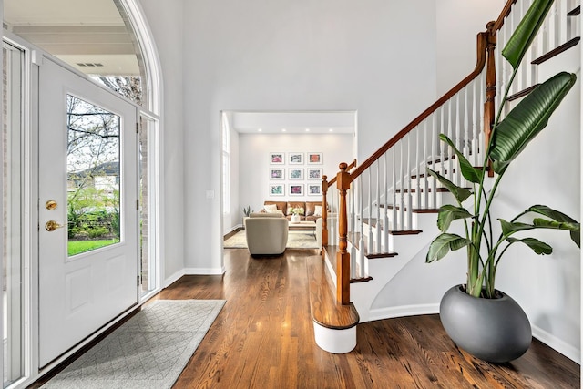entrance foyer with visible vents, a high ceiling, dark wood-style floors, and stairway