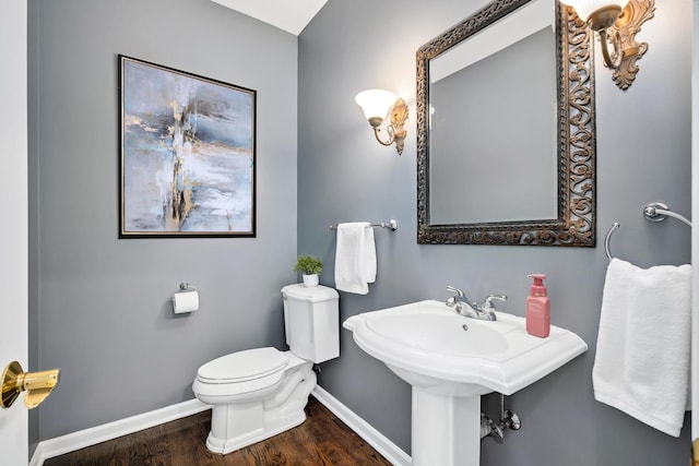 half bath with wood finished floors, baseboards, and toilet