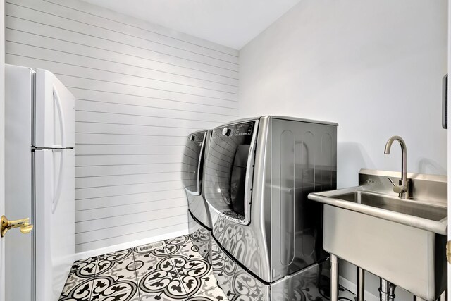 clothes washing area with wood walls, separate washer and dryer, and laundry area