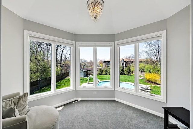 unfurnished room featuring baseboards, a notable chandelier, and carpet