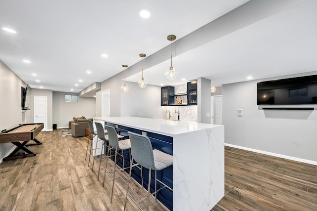 kitchen with recessed lighting, wood finished floors, baseboards, and a breakfast bar area