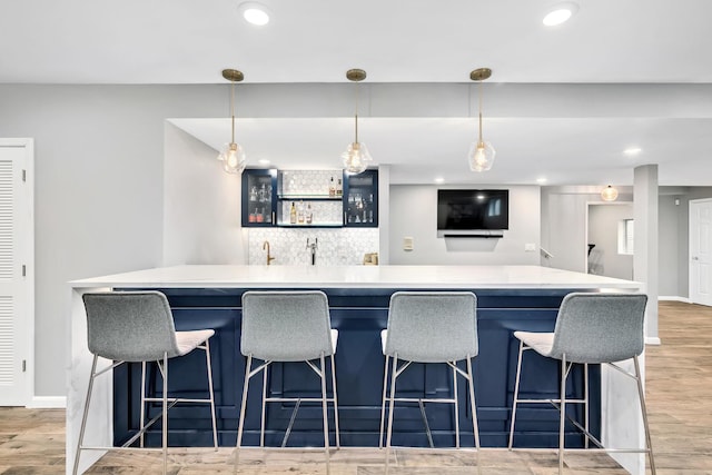 kitchen featuring a center island, light wood-type flooring, light countertops, backsplash, and baseboards