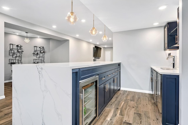 bar with wood finished floors, baseboards, indoor wet bar, and a sink