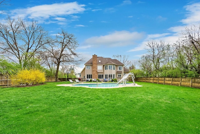 back of house with a fenced in pool, a lawn, a chimney, and a fenced backyard