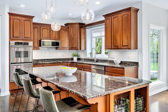kitchen with baseboards, appliances with stainless steel finishes, a sink, and dark wood-type flooring