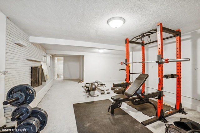 exercise room with a textured ceiling and brick wall