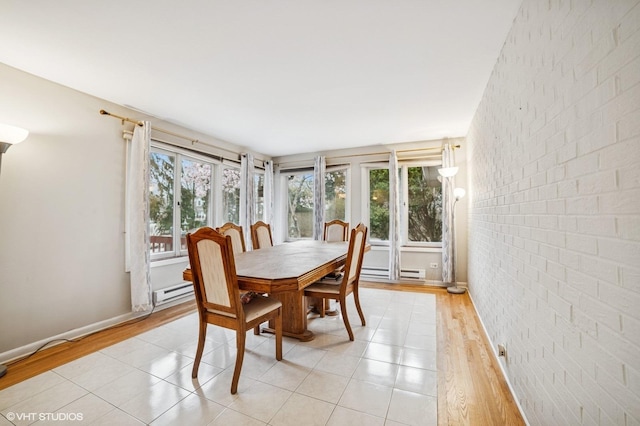 dining area with baseboards, a baseboard radiator, light wood finished floors, and brick wall