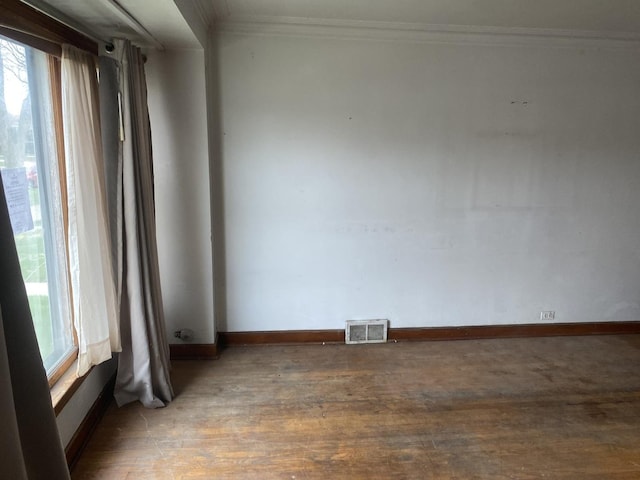 unfurnished room featuring visible vents, plenty of natural light, crown molding, and wood finished floors