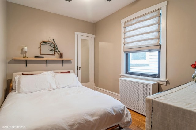 bedroom with radiator and wood finished floors