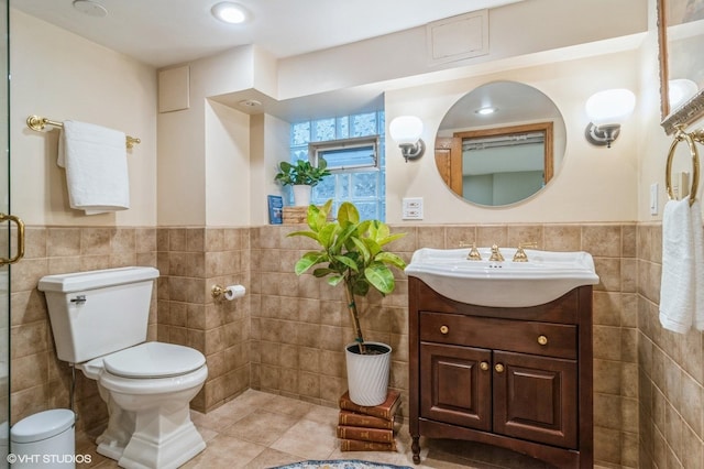 bathroom featuring toilet, tile walls, tile patterned flooring, and a wainscoted wall