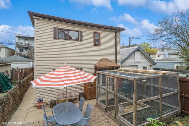 rear view of property featuring exterior structure, a patio area, fence, and outdoor dining space