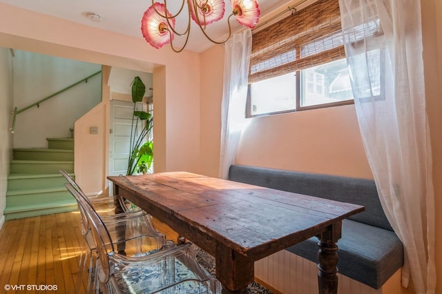 dining area with stairway, a notable chandelier, and hardwood / wood-style flooring