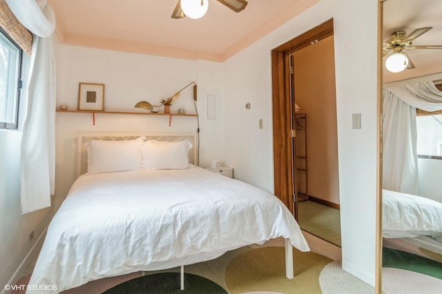 carpeted bedroom featuring baseboards, multiple windows, and a ceiling fan