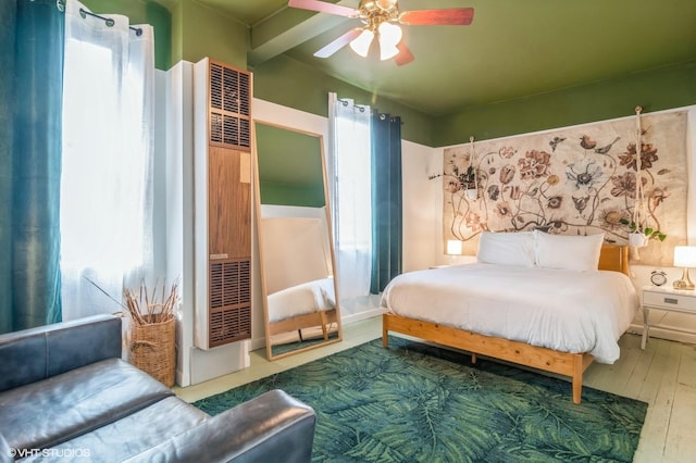 bedroom featuring a ceiling fan, wood finished floors, and a heating unit