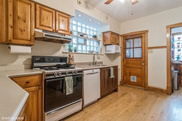 kitchen featuring a sink, dishwasher, light wood-style flooring, under cabinet range hood, and range with gas cooktop
