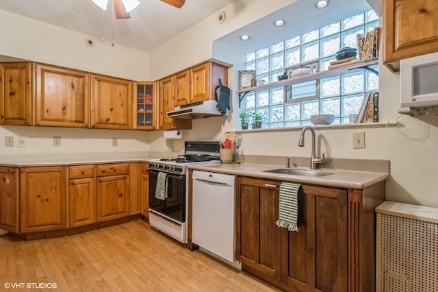 kitchen featuring brown cabinetry, gas range, under cabinet range hood, a sink, and dishwasher