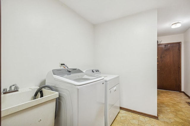 laundry area with a sink, baseboards, laundry area, and washing machine and clothes dryer