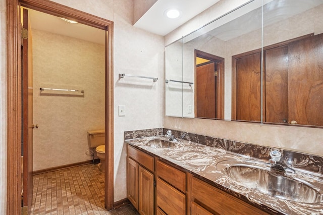 bathroom featuring double vanity, a sink, baseboards, and toilet