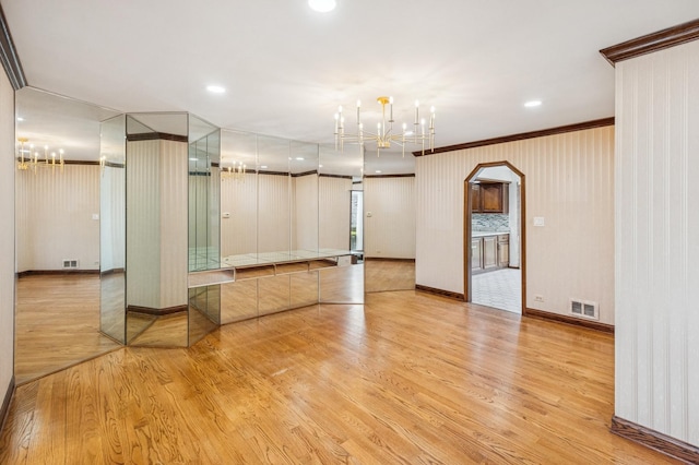unfurnished room featuring crown molding, a notable chandelier, visible vents, and light wood-type flooring