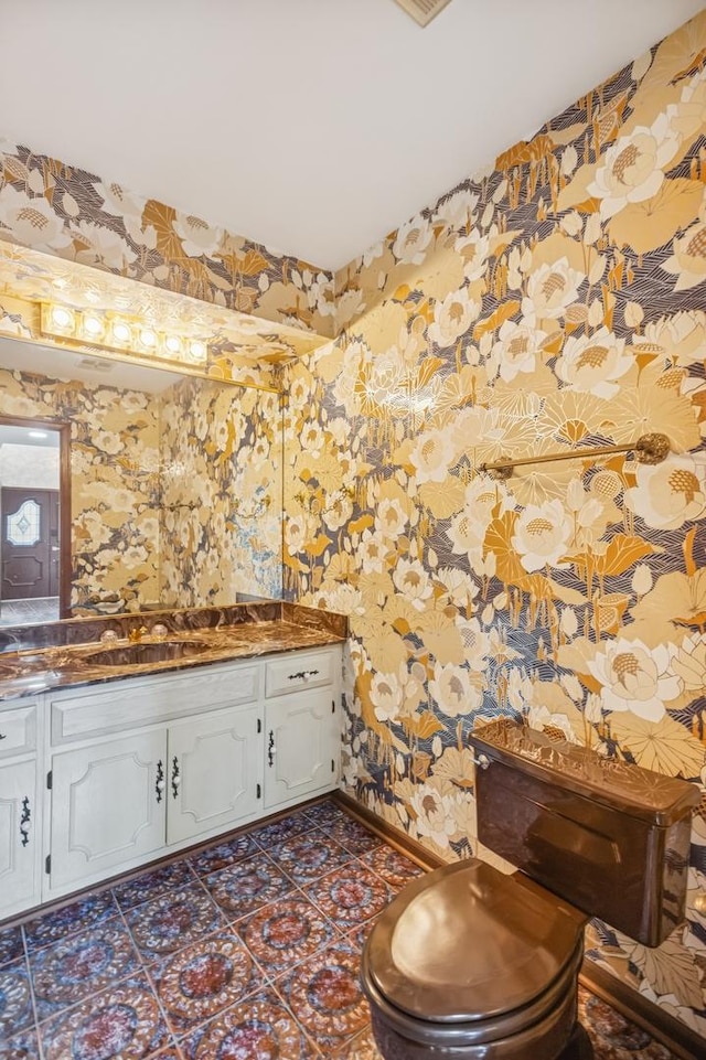 bathroom featuring wallpapered walls, baseboards, and vanity