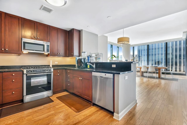 kitchen with light wood-style floors, visible vents, dark countertops, and stainless steel appliances