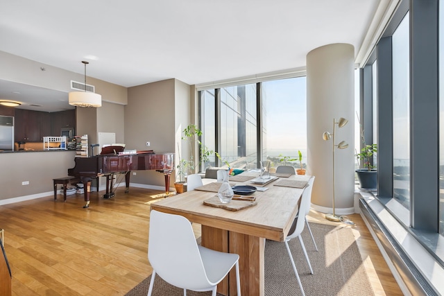 dining space featuring baseboards, visible vents, expansive windows, and light wood finished floors