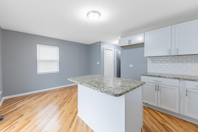 kitchen featuring light wood-style floors, decorative backsplash, baseboards, and a center island