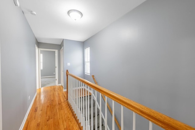 hallway featuring an upstairs landing, light wood-style flooring, and baseboards