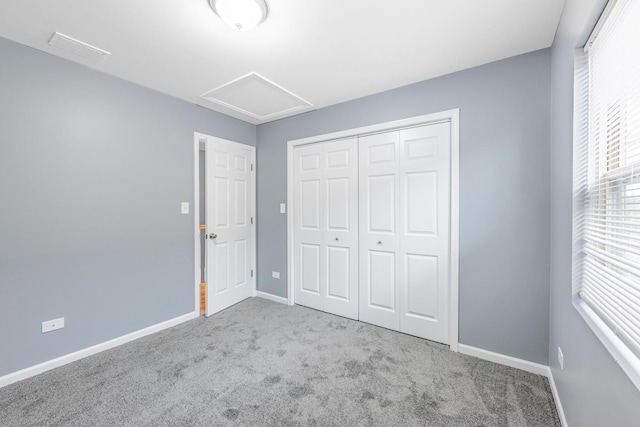 unfurnished bedroom with attic access, visible vents, baseboards, and carpet floors