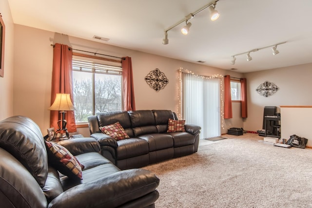 living room featuring rail lighting, carpet flooring, and visible vents