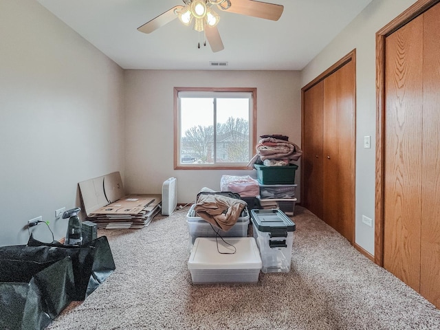 living area featuring carpet floors, visible vents, and ceiling fan
