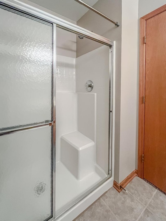 bathroom featuring baseboards, tile patterned floors, and a stall shower