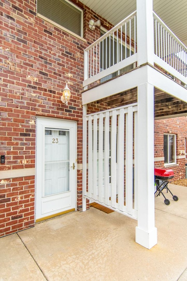 doorway to property featuring brick siding and a balcony