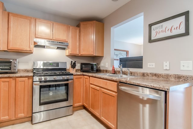kitchen with a sink, light brown cabinetry, a toaster, stainless steel appliances, and under cabinet range hood